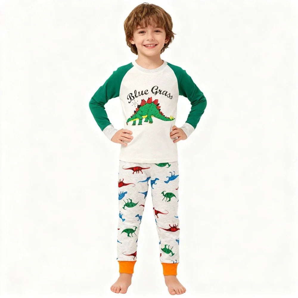 Kids Animal Pajama Set in white cotton knit, with green raglan sleeves, dinosaur prints, and bright orange cuffs.
